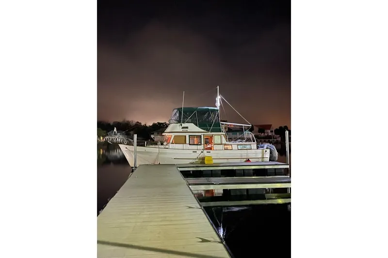 Slide: The Image of 1981 Marine Trader Double Cabin yacht docked at night, illuminated by soft lighting. - 17