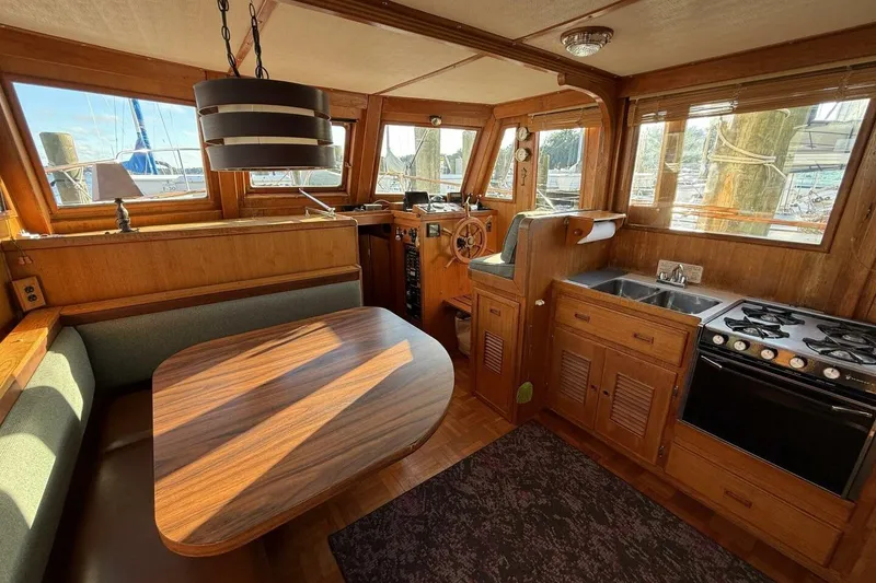 Slide: The Image of 1981 Marine Trader Double Cabin interior with wood finish, dining area, and kitchen amenities. - 18