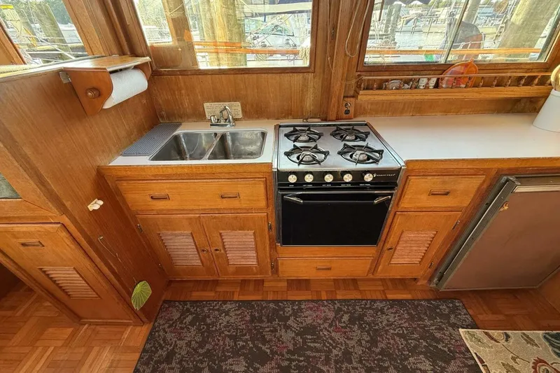 Slide: The Image of 1981 Marine Trader Double Cabin kitchen with stove, sink, and wooden cabinetry. - 24