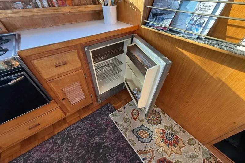 Slide: The Image of 1981 Marine Trader Double Cabin interior with open mini fridge and wooden cabinetry. - 25