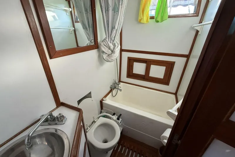 Slide: The Image of 1981 Marine Trader Double Cabin bathroom with sink, toilet, and bathtub, featuring wood accents. - 35