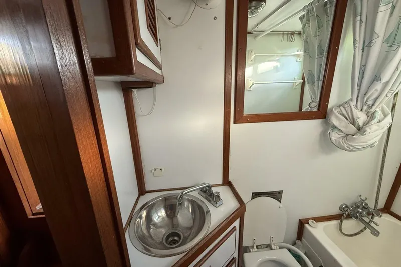Slide: The Image of 1981 Marine Trader Double Cabin bathroom with sink, mirror, and shower curtain. - 36