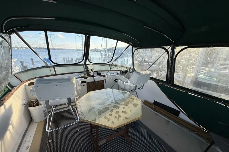 Slide: The Image of 1981 Marine Trader Double Cabin interior with helm, chairs, and table overlooking marina. - 38