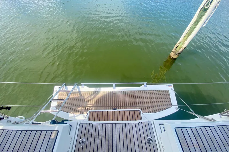 Slide: The Image of Beneteau Oceanis 35 (2016) yacht stern view with teak deck and water backdrop. - 44