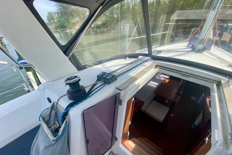 Slide: The Image of 2016 Beneteau Oceanis 35 sailboat cockpit and cabin entrance, docked by a serene waterfront. - 47