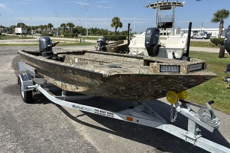 Slide: The Image of 2026 SeaArk 1752 Slayer boat on trailer, camo design, parked outdoors. - 5