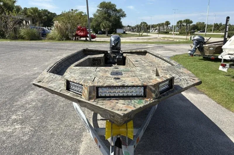 Slide: The Image of 2026 SeaArk 1752 Slayer boat with camouflage design and LED lights on a trailer. - 6