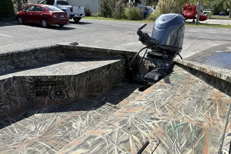 Slide: The Image of 2026 SeaArk 1752 Slayer boat with camouflage design and outboard motor in a parking lot. - 8