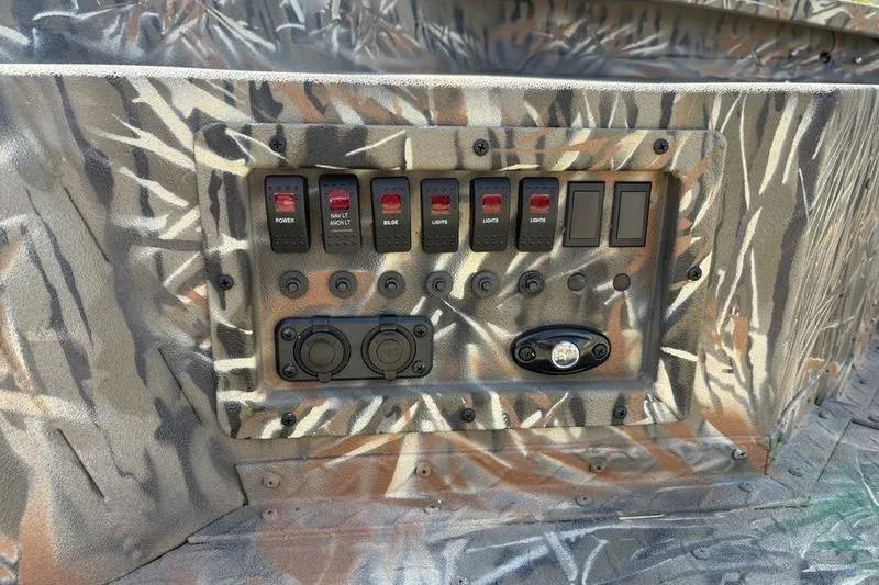 Slide: The Image of Control panel of 2026 SeaArk 1752 Slayer boat with camouflage design and multiple switches. - 9