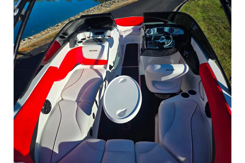 Slide: The Image of 2012 Sea-Doo Sport Boats 210 Wake interior with red and white seating, steering console, and table. - 10