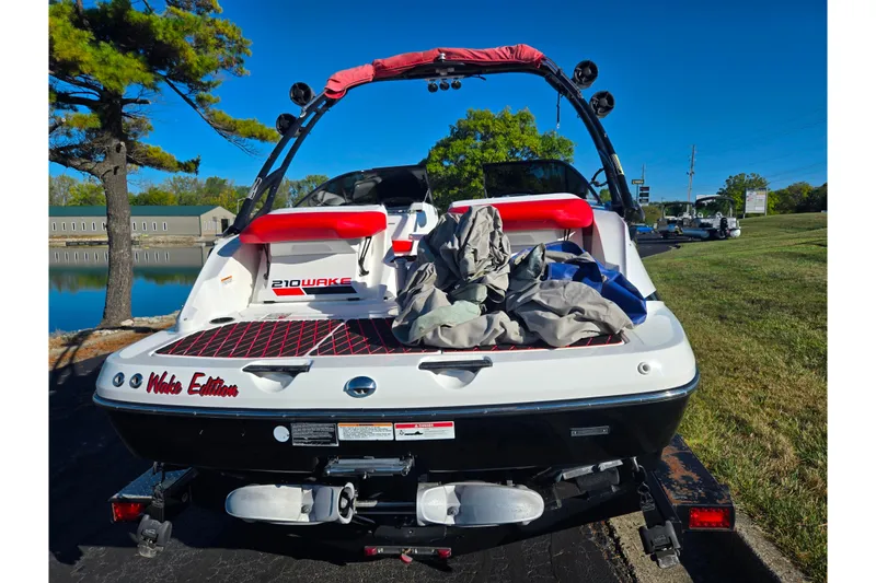 Slide: The Image of 2012 Sea-Doo 210 Wake Edition boat on trailer, parked near a lake. - 2