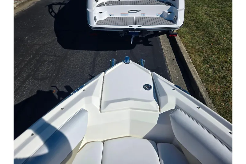 Slide: The Image of 2007 Larson LXi 228 boat interior with white seating, parked on a paved road. - 17
