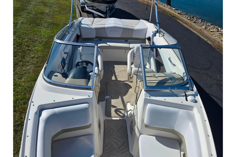 Slide: The Image of 2007 Larson LXi 228 boat interior with seating and steering wheel, docked by the water. - 19
