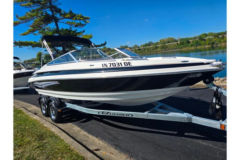 Slide: The Image of 2007 Larson LXi 228 boat on trailer by a lake under clear blue sky. - 8