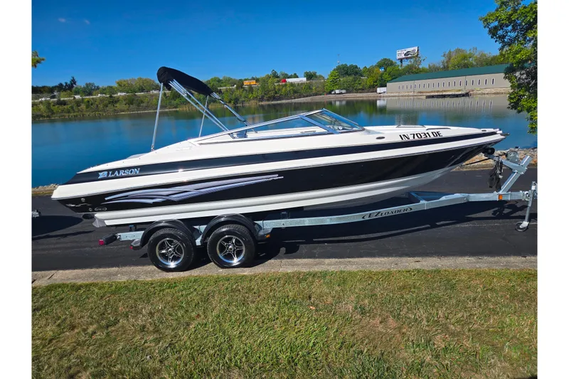 Slide: The Image of 2007 Larson LXi 228 boat on trailer by a lake, under clear blue sky. - 9