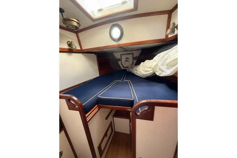 Slide: The Image of Interior cabin of 1981 Kaiser 34' Gale Force offshore cutter, featuring cozy bedding and wooden accents. - 13