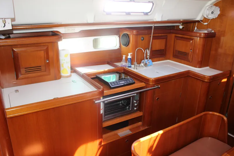 Slide: The Image of 2001 Beneteau 411 yacht kitchen with wooden cabinetry, sink, and oven. - 27