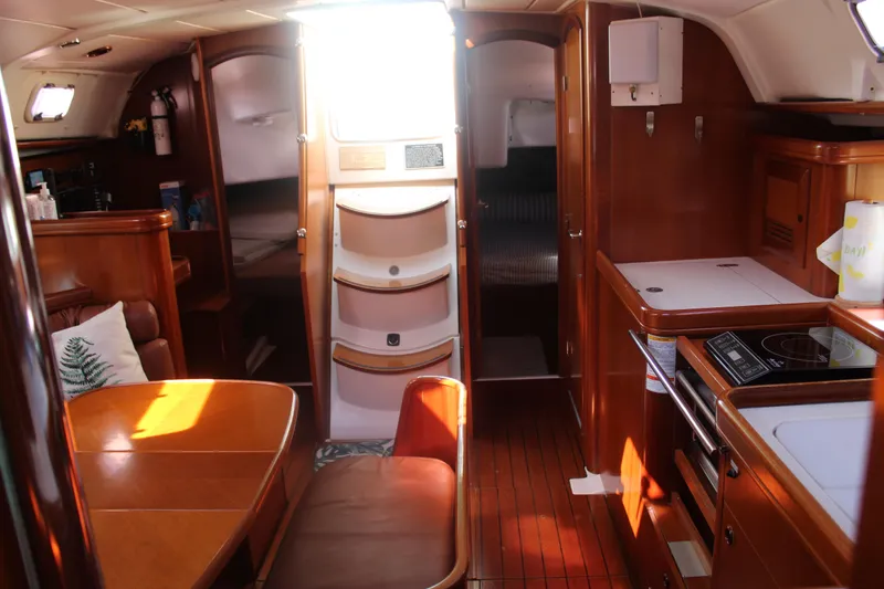 Slide: The Image of Interior of 2001 Beneteau 411 sailboat with wood finish and compact kitchen area. - 34