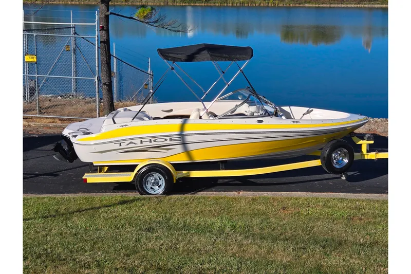 The Image of 2006 Tahoe Q4 Sport boat on trailer by a lake, featuring a yellow and white design. - 0