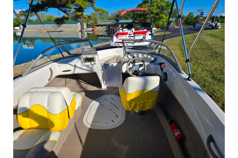 Slide: The Image of 2006 Tahoe Q4 Sport boat interior with yellow seats and steering wheel, docked by a lake. - 10