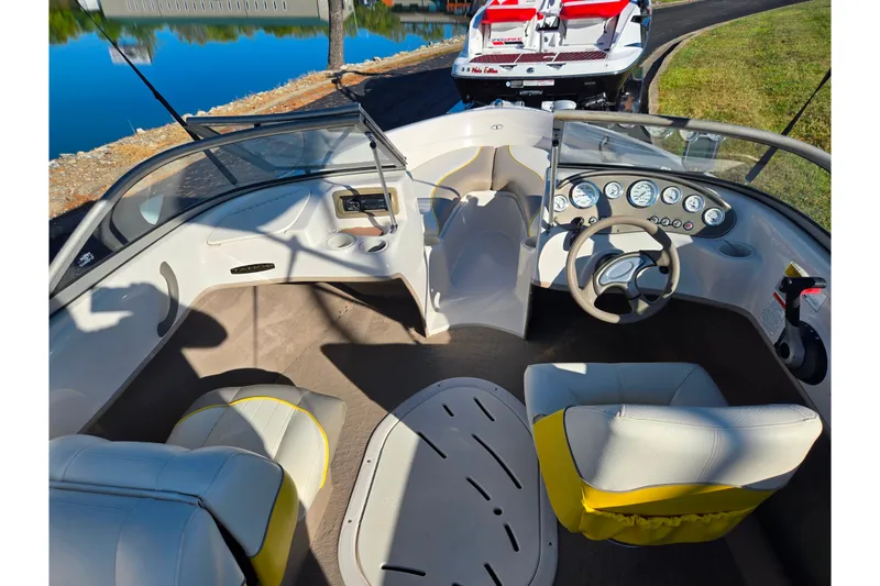 Slide: The Image of 2006 Tahoe Q4 Sport boat interior with steering wheel and seating, near a calm lake. - 11