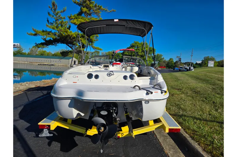 Slide: The Image of 2006 Tahoe Q4 Sport boat on trailer, parked near a serene lake under clear blue skies. - 2