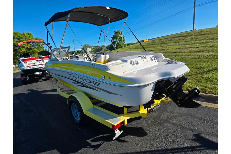 Slide: The Image of 2006 Tahoe Q4 Sport boat on trailer, yellow and white, with canopy, parked on road. - 3