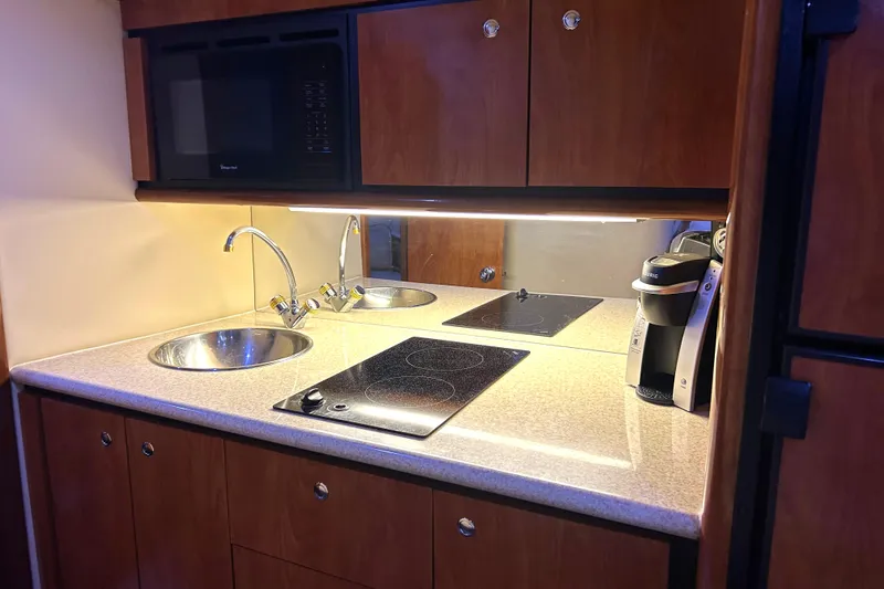 Slide: The Image of 2005 Fountain 48 Express Cruiser kitchen with sink, stovetop, microwave, and coffee maker. - 8