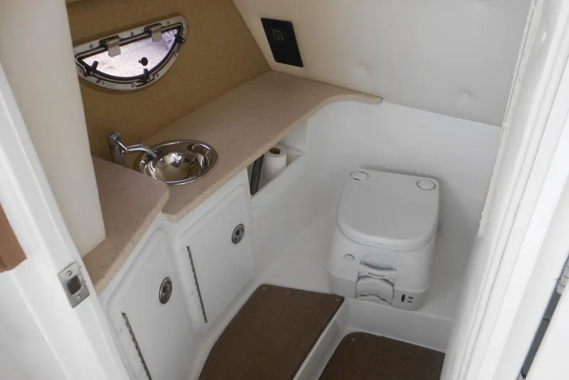 Slide: The Image of 2015 Cobalt 296 boat interior with compact bathroom, sink, and toilet. - 16