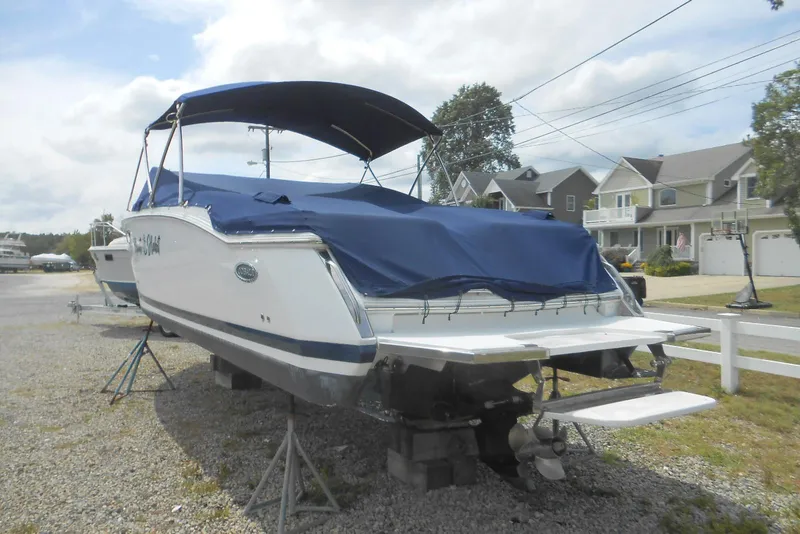 Slide: The Image of 2015 Cobalt 296 boat with blue cover, parked on gravel near residential area. - 5