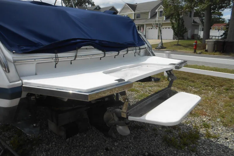 Slide: The Image of 2015 Cobalt 296 boat with covered stern, swim platform, and propeller, parked on gravel. - 6