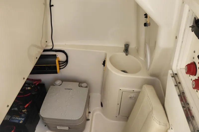 Slide: The Image of 2007 Triton 2895 CC boat interior with sink, battery, and portable toilet. - 19