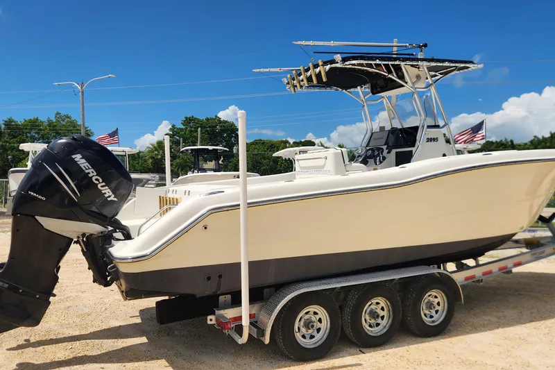 Slide: The Image of 2007 Triton 2895 CC boat on trailer with Mercury outboard, clear blue sky background. - 2
