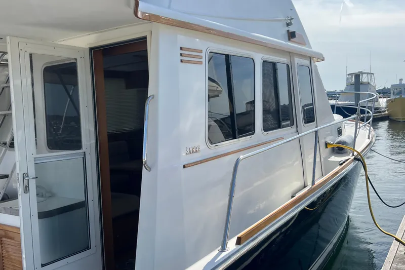 Slide: The Image of 2005 Sabre Flybridge yacht docked, showcasing sleek design and spacious cabin entry. - 11