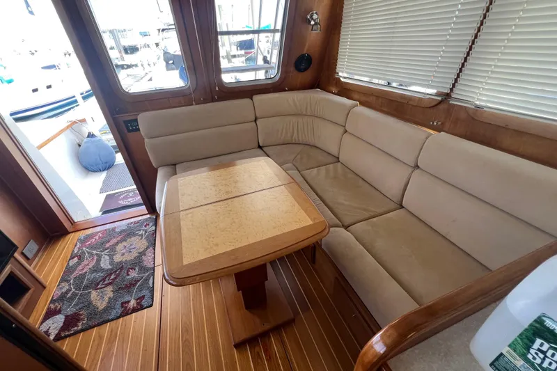 Slide: The Image of 2005 Sabre Flybridge interior with beige seating, wooden table, and floral rug. - 42