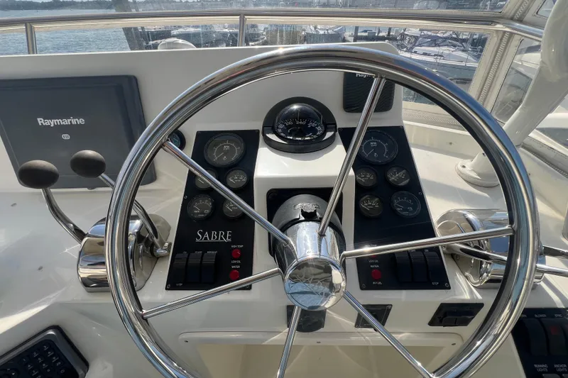 Slide: The Image of 2005 Sabre Flybridge helm with steering wheel, gauges, and Raymarine navigation system. - 52