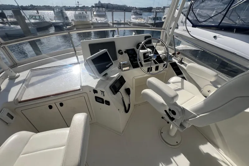 Slide: The Image of 2005 Sabre Flybridge helm with steering wheel, navigation equipment, and white seating. - 58