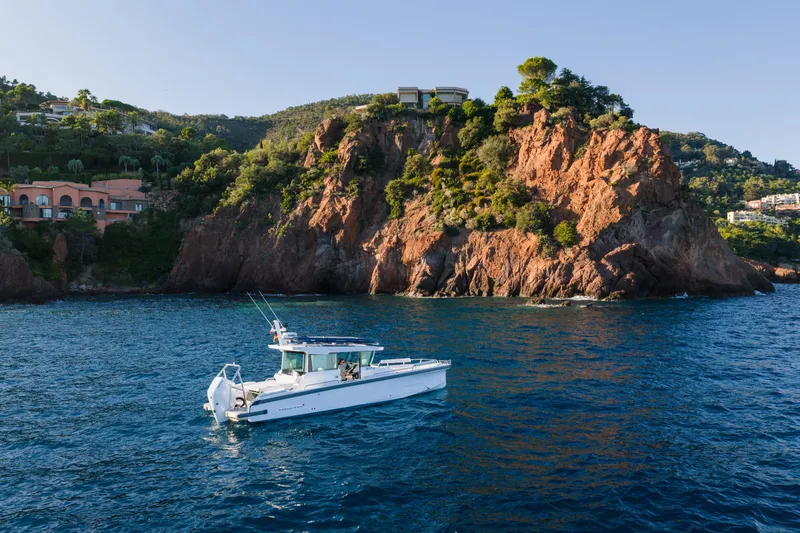 Slide: The Image of 2026 Axopar 29 XC boat cruising near rocky coastline with lush greenery. - 5
