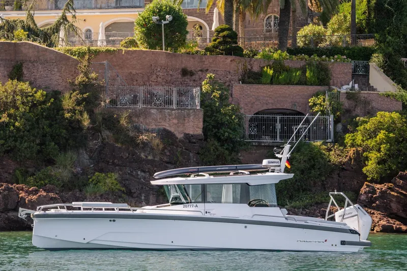 Slide: The Image of 2026 Axopar 29 XC boat on water, scenic villa backdrop, lush greenery. - 6