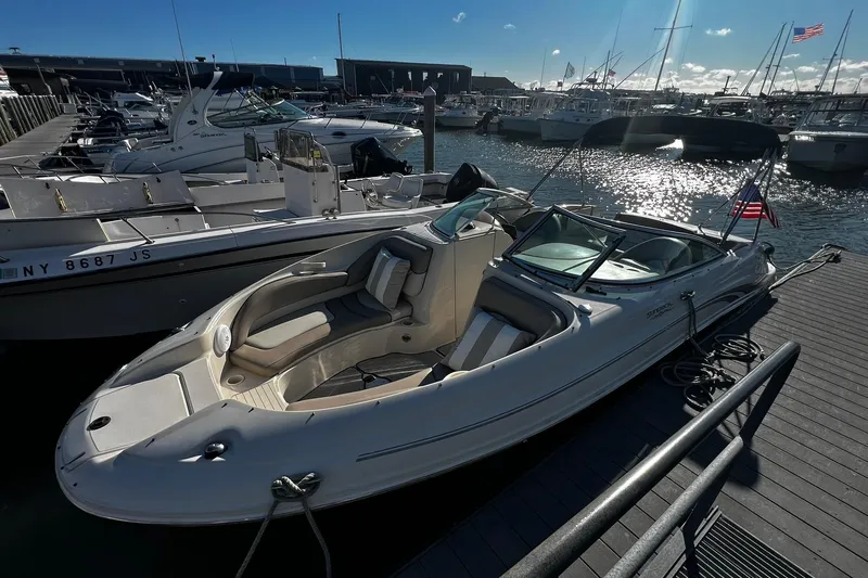 Slide: The Image of 2003 Sea Ray 220 Sundeck boat docked at marina, sunny day, American flag visible. - 2