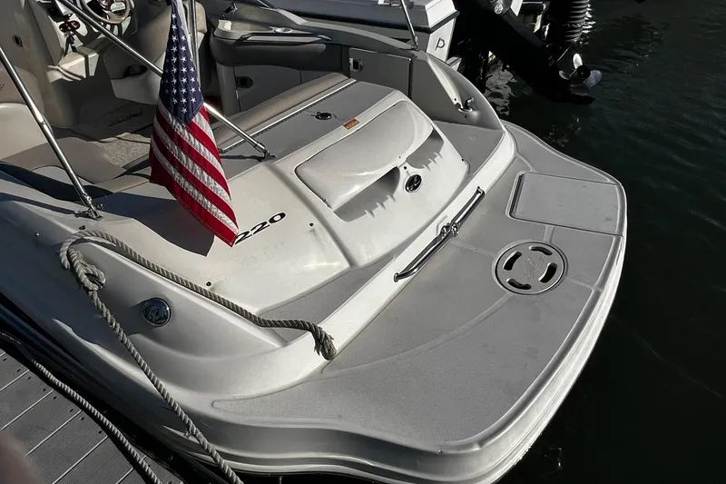 Slide: The Image of 2003 Sea Ray 220 Sundeck boat with American flag, docked by the water. - 3