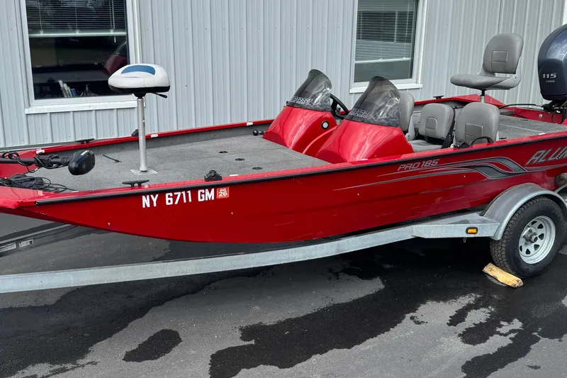 The Image of 2013 Alumacraft Pro 185 red fishing boat on trailer, parked outside a building. - 1