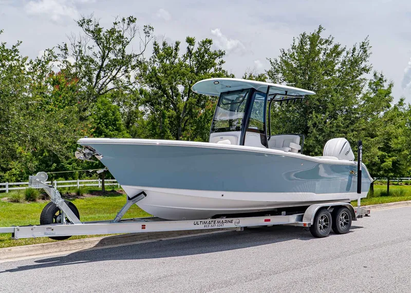The Image of 2026 Sea Hunt Ultra 245 SE boat on trailer, parked on a road with trees in background. - 1