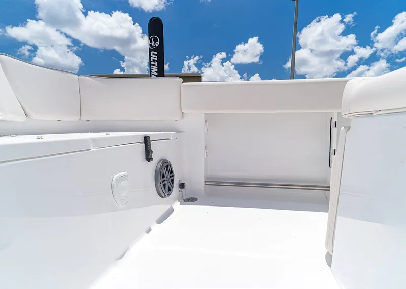 Slide: The Image of 2026 Sea Hunt Ultra 245 SE boat interior with white seating and speaker, under blue sky. - 10