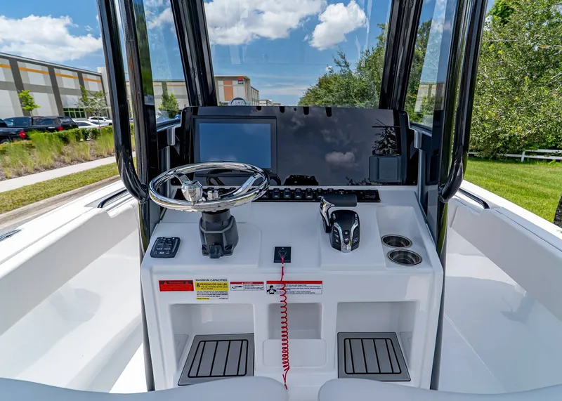 Slide: The Image of 2026 Sea Hunt Ultra 245 SE boat console with steering wheel and controls, outdoors. - 14