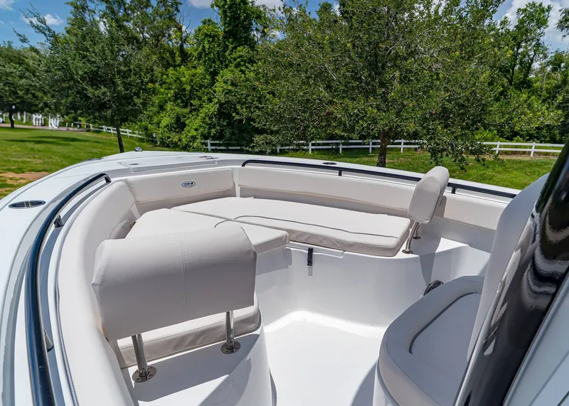 Slide: The Image of 2026 Sea Hunt Ultra 245 SE boat interior with cushioned seating and lush greenery background. - 21