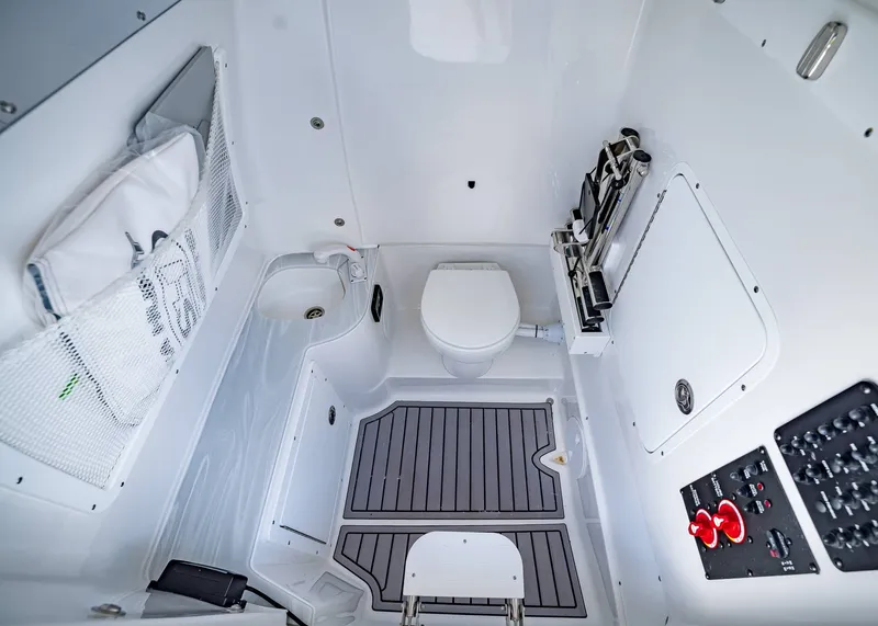 Slide: The Image of Interior of 2026 Sea Hunt Ultra 305 SE boat, featuring a compact bathroom with toilet and sink. - 31