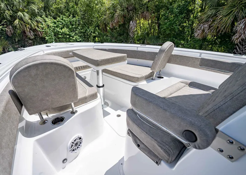 Slide: The Image of 2026 Sea Hunt Ultra 305 SE boat interior with cushioned seating and table, surrounded by lush greenery. - 32