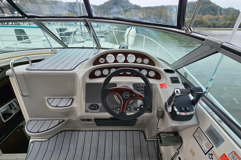Slide: The Image of 2004 Monterey 282 Cruiser helm with gauges, steering wheel, and throttle controls on a calm river. - 10