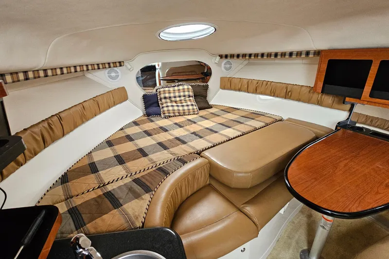 Slide: The Image of 2004 Monterey 282 Cruiser cabin interior with plaid bedding and wooden table. - 14